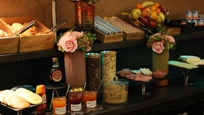 A buffet with various food items, condiments, and decorative flowers. - Le patio Bastille (Paris)