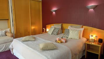 A hotel room with a large bed, two bedside tables, and a wardrobe.