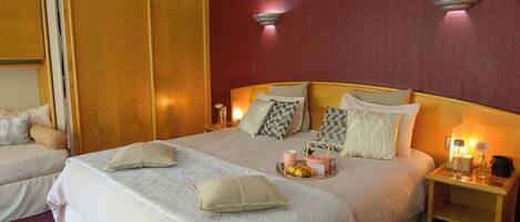 A hotel room with a large bed, two bedside tables, and a wardrobe.