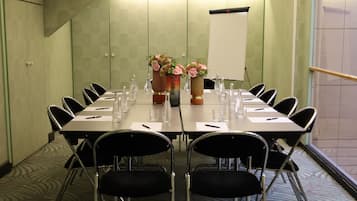 A conference room with a long table, chairs, water bottles, and vases with flowers.