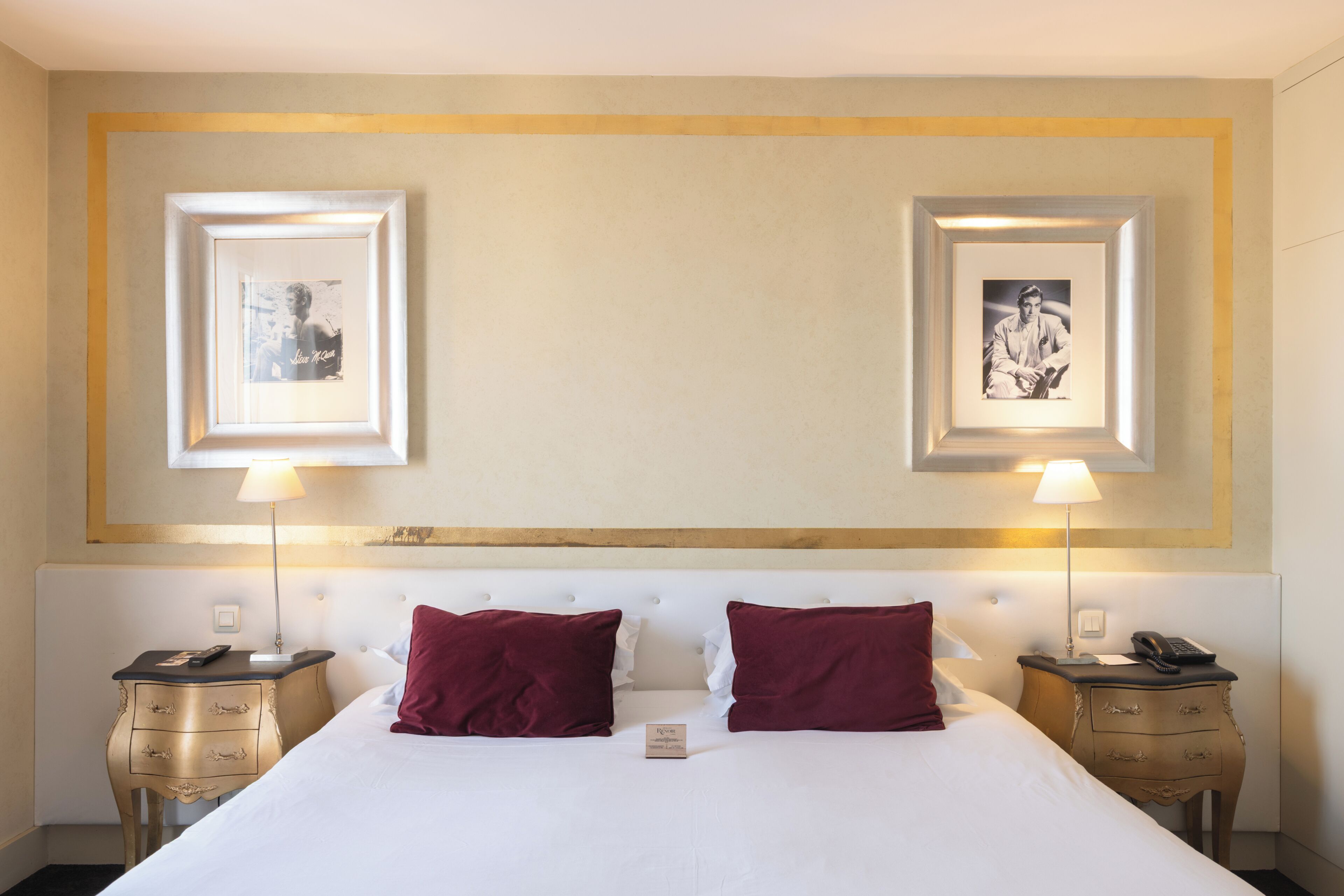 Een hotelkamer met een groot bed, twee nachtkastjes, twee lampen en twee ingelijste foto's aan de muur.
