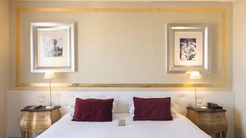 Een hotelkamer met een groot bed, twee nachtkastjes, twee lampen en twee ingelijste foto's aan de muur.