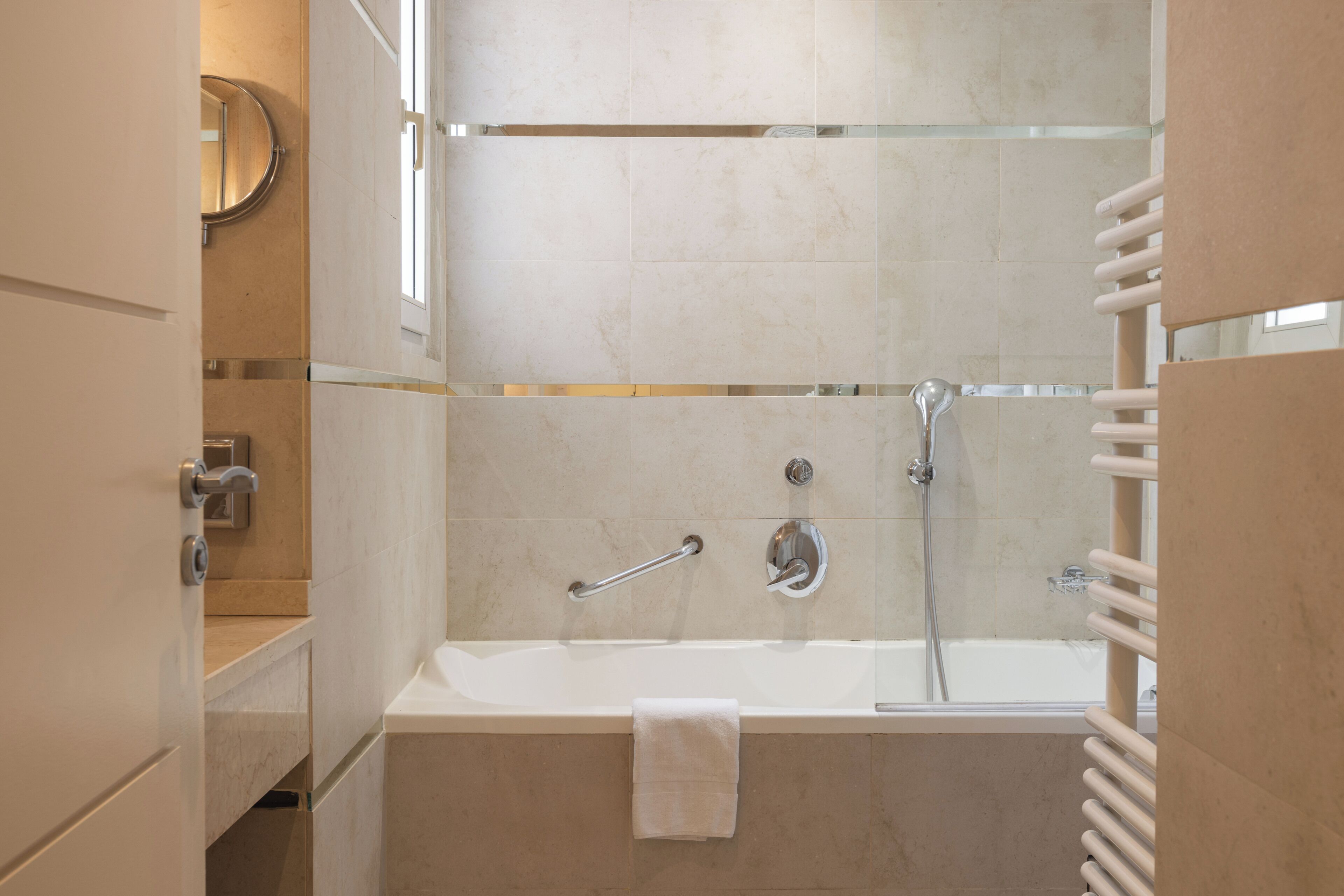 Un baño moderno con bañera, cabina de ducha de vidrio y perchero para toallas.