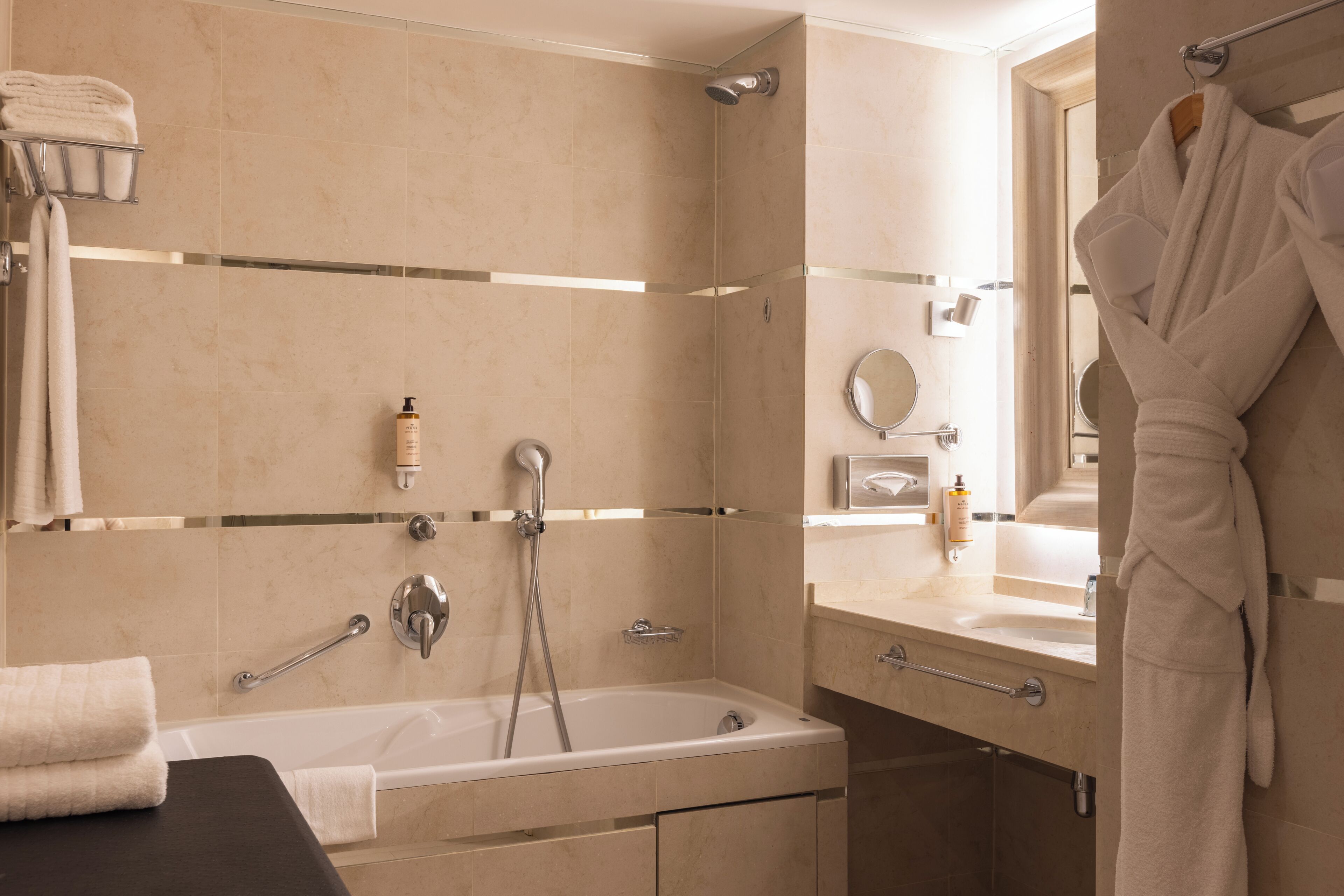 A bathroom with a bathtub, a shower, a vanity with a mirror, and a towel rack.