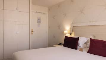 Una habitación de hotel con cama, mesita de noche, lámpara, teléfono y armario.