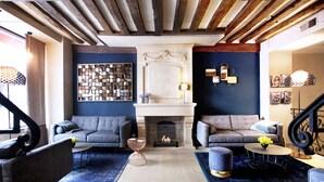 A modern living room with a fireplace, two sofas, a coffee table, and a rug. - Hôtel Sèvres Saint Germain (Paris)