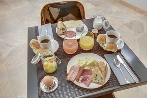 A breakfast tray with croissants, eggs, ham, and various beverages on a table. - Hôtel Sèvres Saint Germain (Paris)