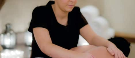 A massage therapy session in a room with a massage table, a bottle, and a white towel.