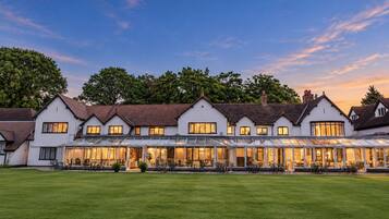 A large, multi-story building with a covered patio area and a well-maintained lawn in front.