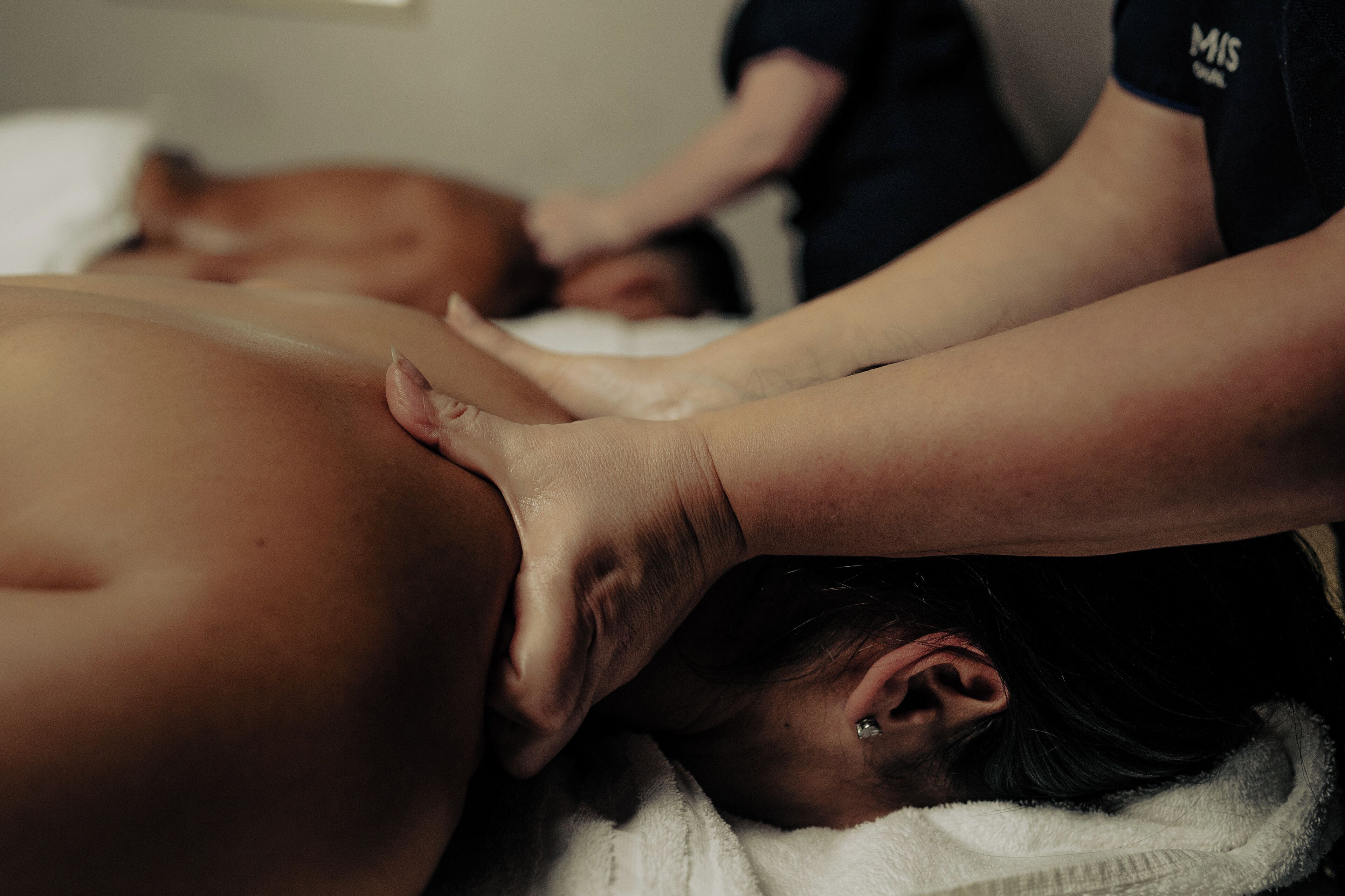 A massage therapy session in progress with a client lying face down on a massage table.