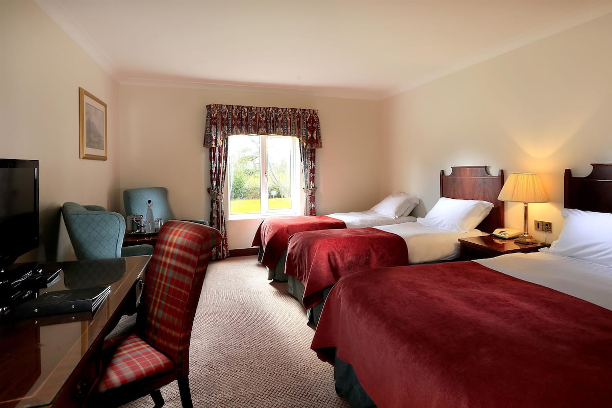 A hotel room with two beds, a desk with a computer, a chair, and a television.