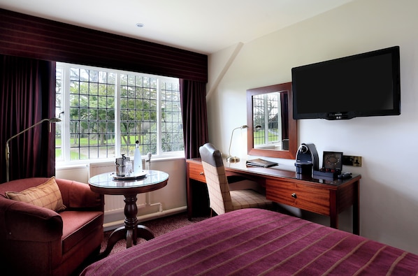 A hotel room with a bed, a desk, a chair, a TV, and a window with curtains. - Macdonald Craxton Wood Hotel & Spa, Chester (Ellesmere Port)