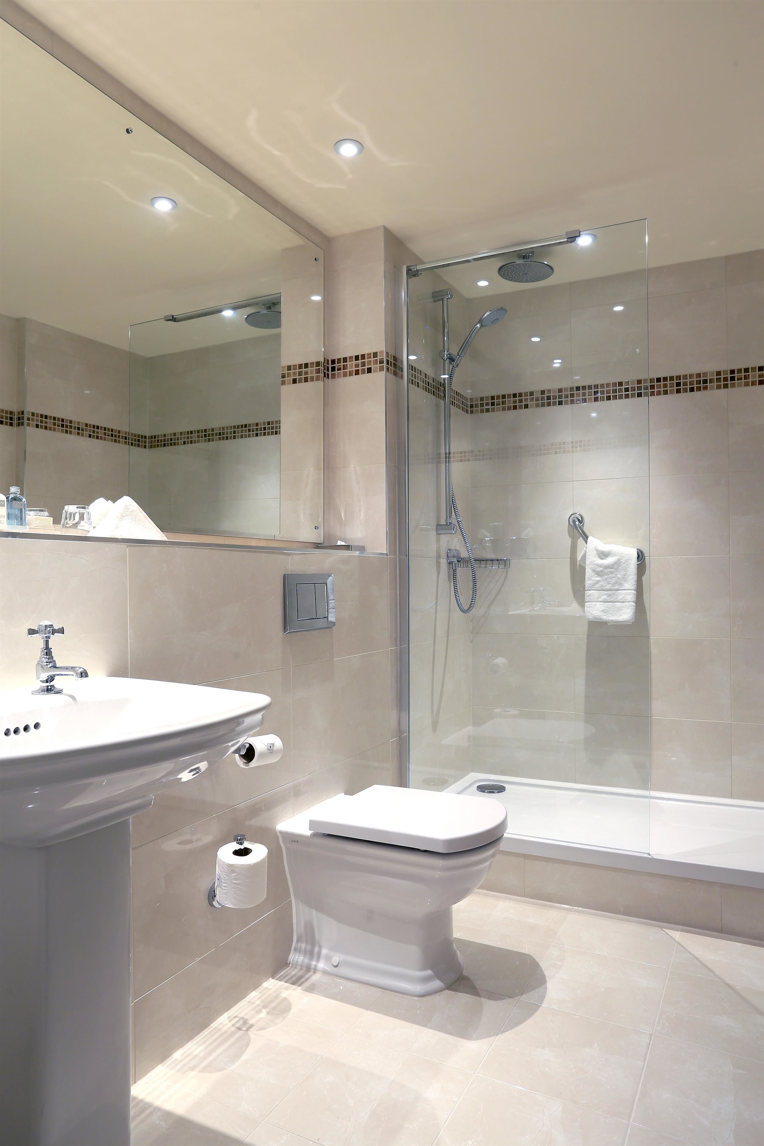 A modern bathroom with a glass-enclosed shower, a toilet, and a sink.