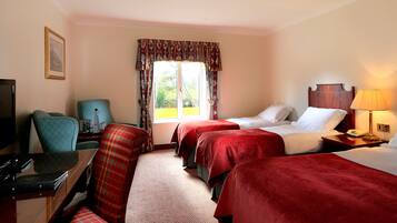 A hotel room with two beds, a desk with a chair, a television, and a window with curtains.