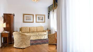 A living room with a sofa, two armchairs, a wooden cabinet, a small table, and two framed pictures on the wall.
