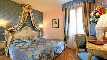 Un dormitorio con una cama con dosel, un escritorio con una silla, un televisor y un jarrón con flores.