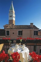 Tavolo apparecchiato all'aperto, con un edificio e una torre sullo sfondo.
