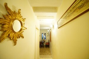Um corredor com um espelho decorativo e um quadro emoldurado nas paredes.
