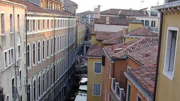 A balcony with a table set for breakfast overlooking a canal in a historic city. - San Marco Palace (Venice)