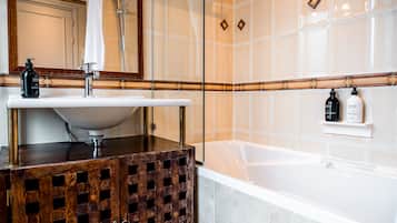 Un baño con un lavamanos blanco, un armario de madera, un espejo, una ducha y una bañera.