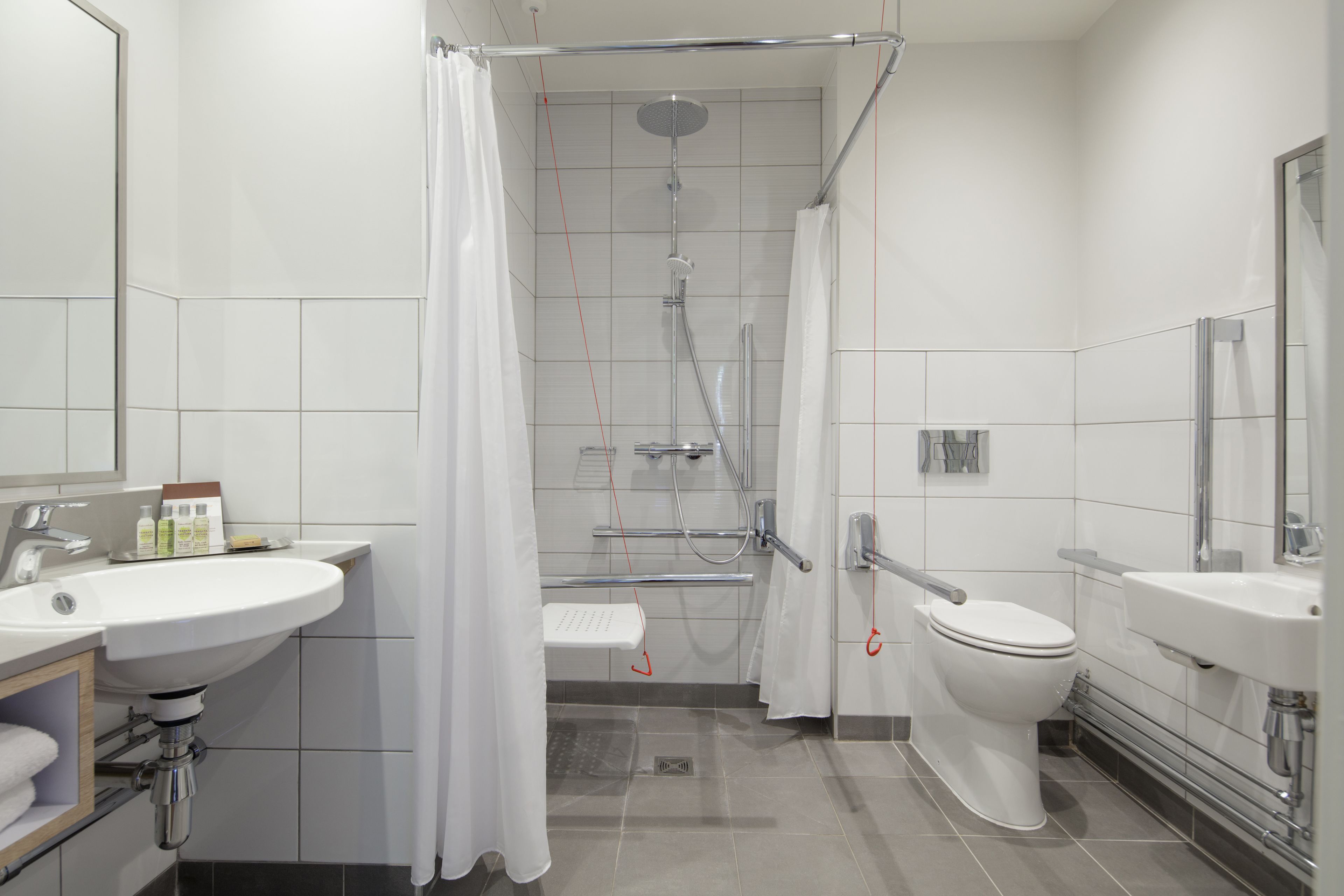 A modern bathroom with a shower, toilet, and two sinks.