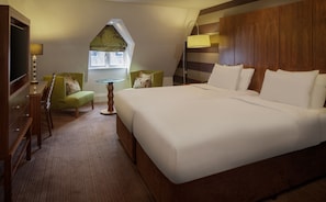 A hotel room with a large bed, two chairs, a small table, and a TV. - The DoubleTree by Hilton Stratford-upon-Avon (Stratford-upon-Avon)