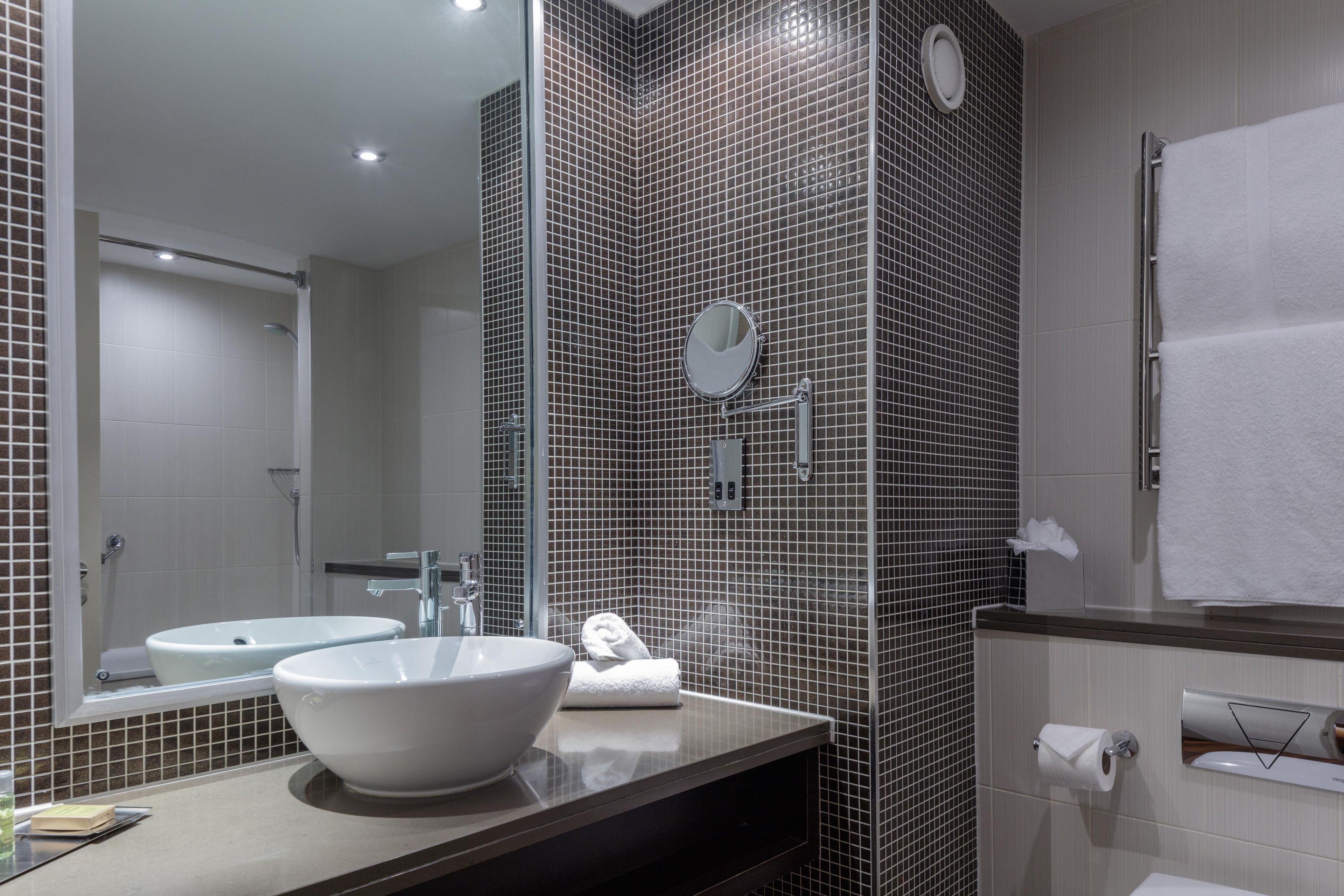 Un baño moderno con dos lavamanos, un espejo grande y un perchero para toallas.