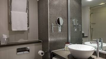 A bathroom with a large white sink, two mirrors, a towel rack, and a shower.