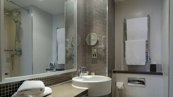 Un baño moderno con lavamanos, espejo y ducha.