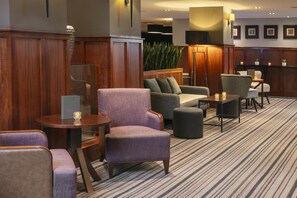 A hotel lobby with a seating area, a reception desk, and a large plant. - The DoubleTree by Hilton Stratford-upon-Avon (Stratford-upon-Avon)