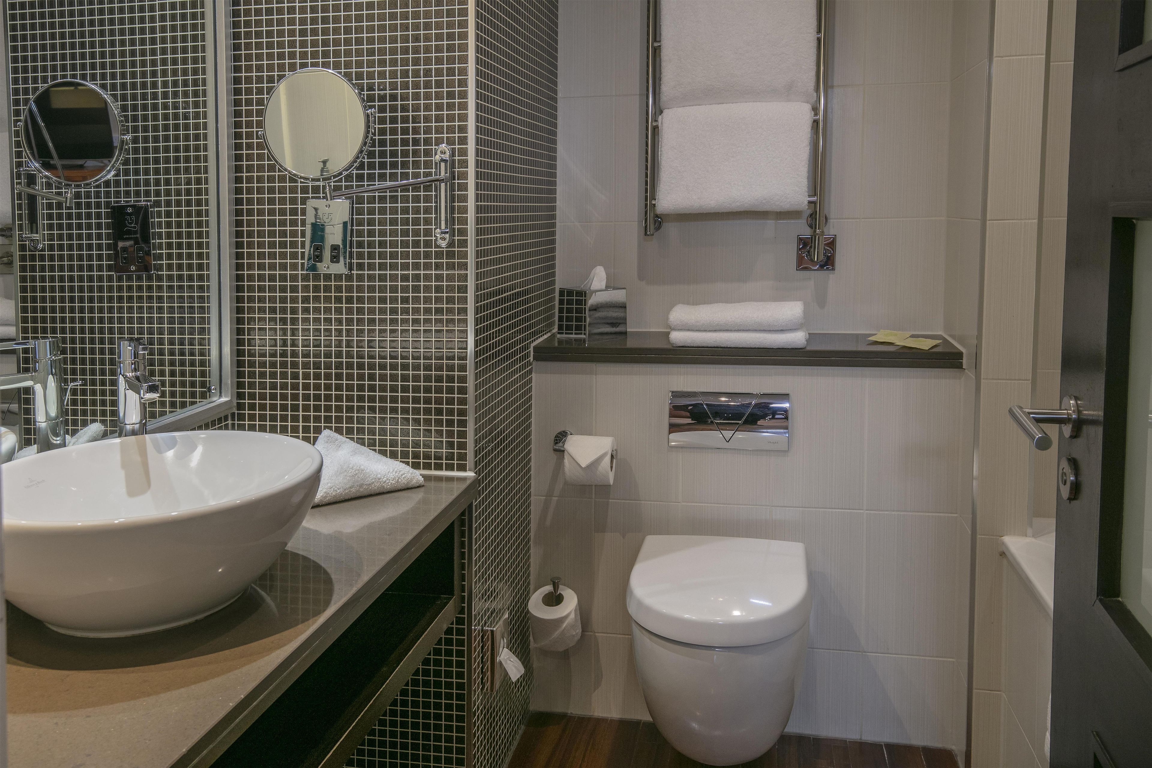 A bathroom with a sink, mirror, toilet, and towel rack.