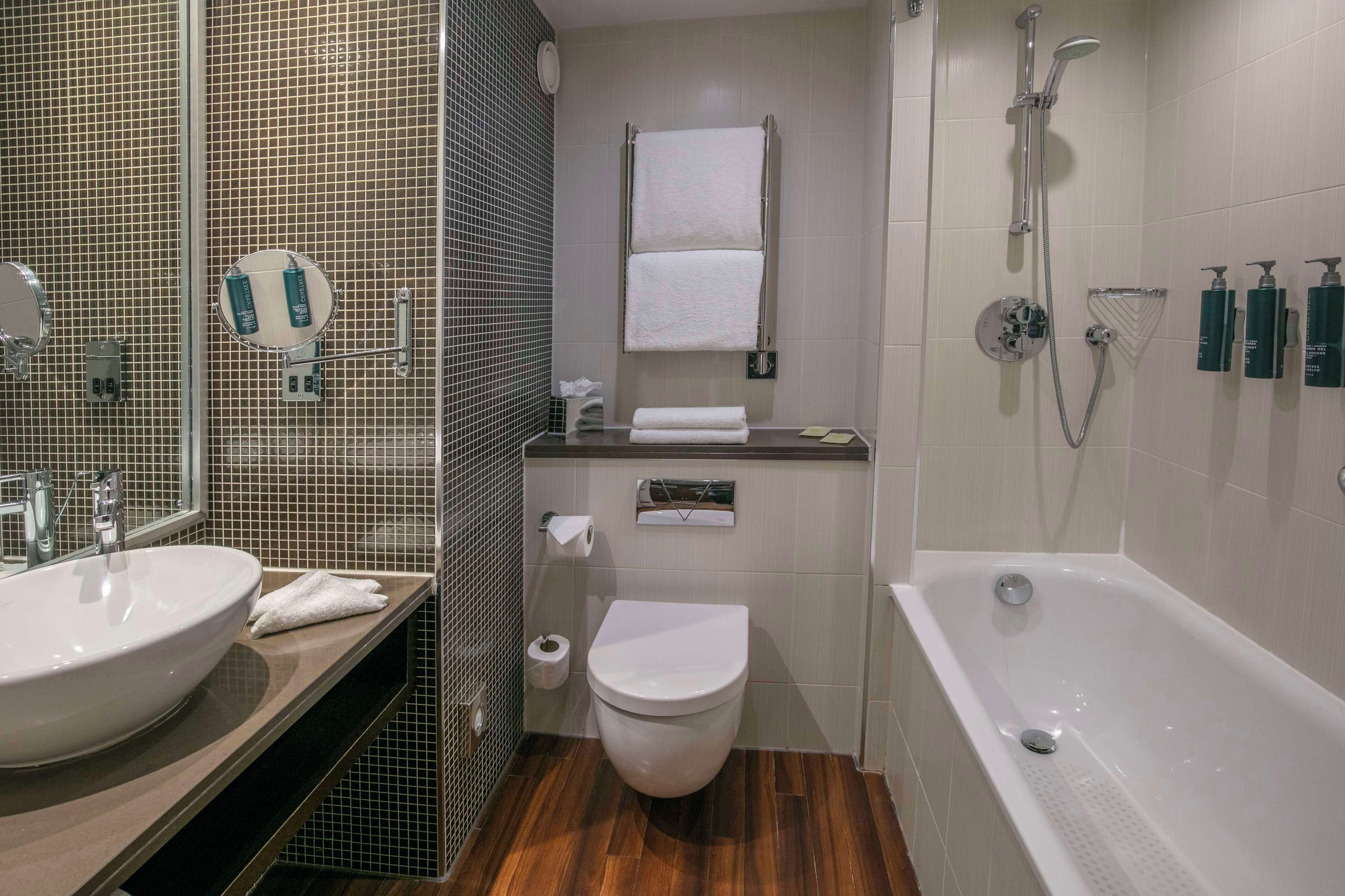 A modern bathroom with two sinks, a toilet, and a bathtub.