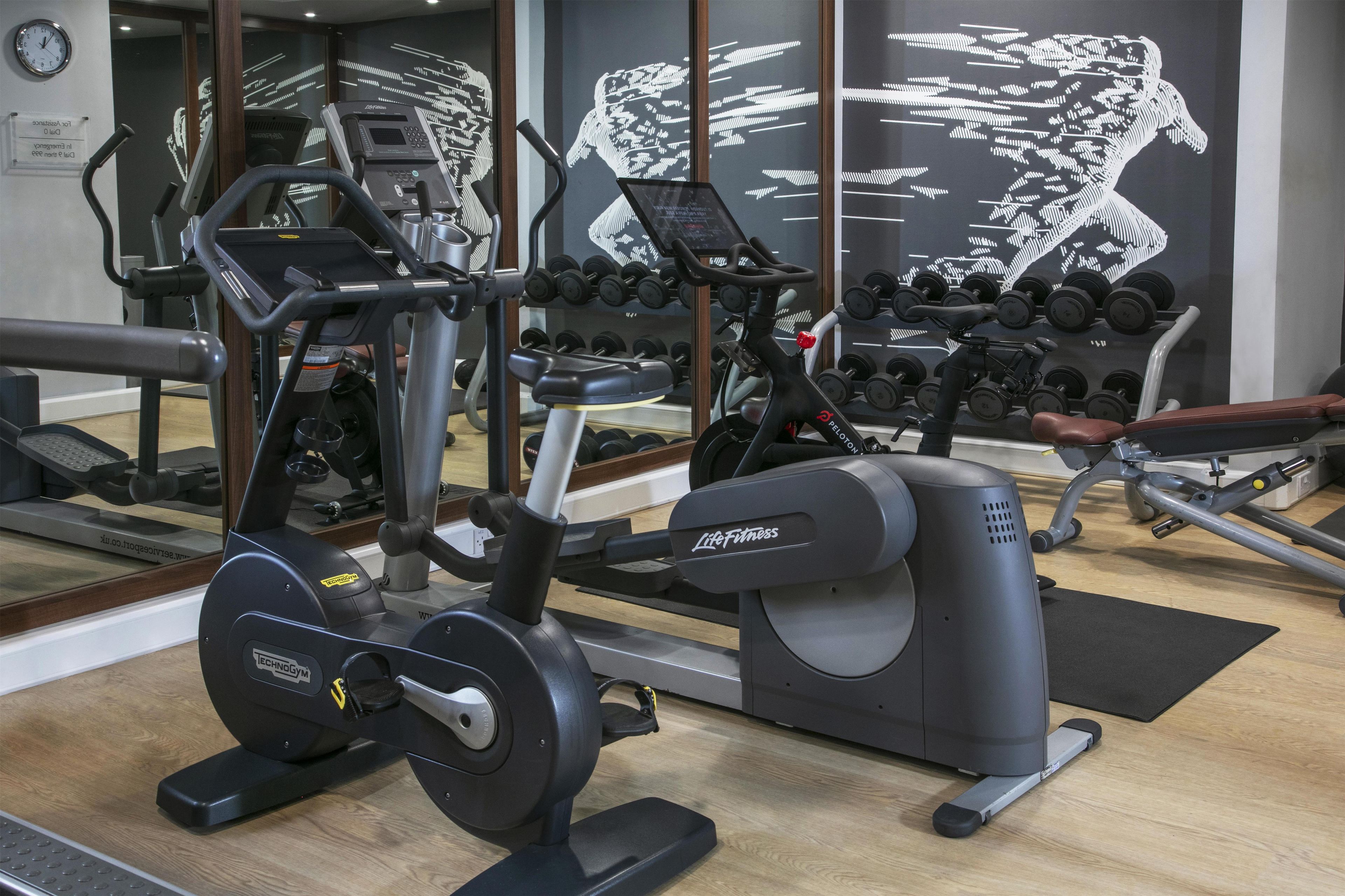 A gym with exercise equipment, a mirror, and a wall with a digital art display.