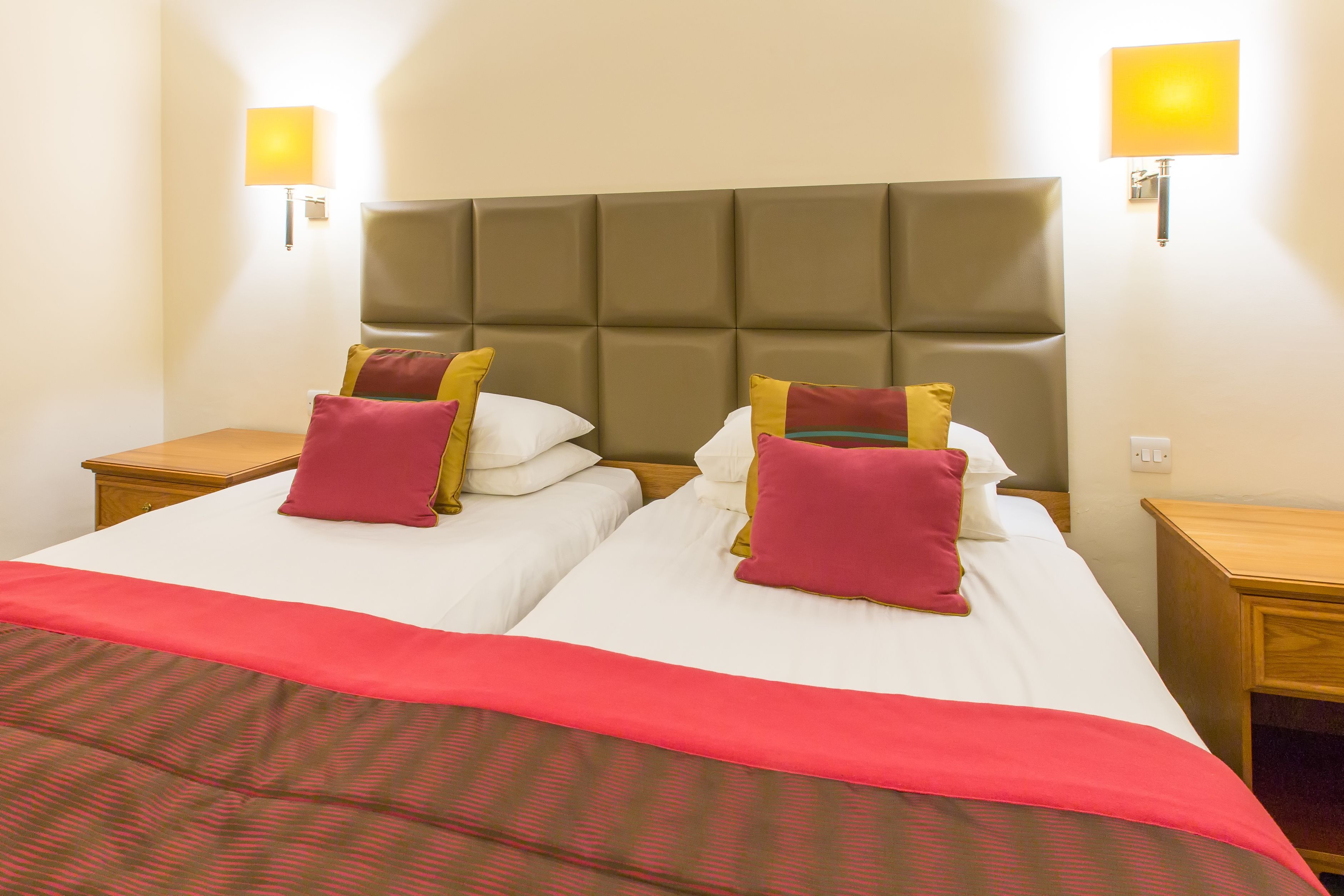 A double bed with a headboard, two bedside tables, and two wall-mounted lamps.