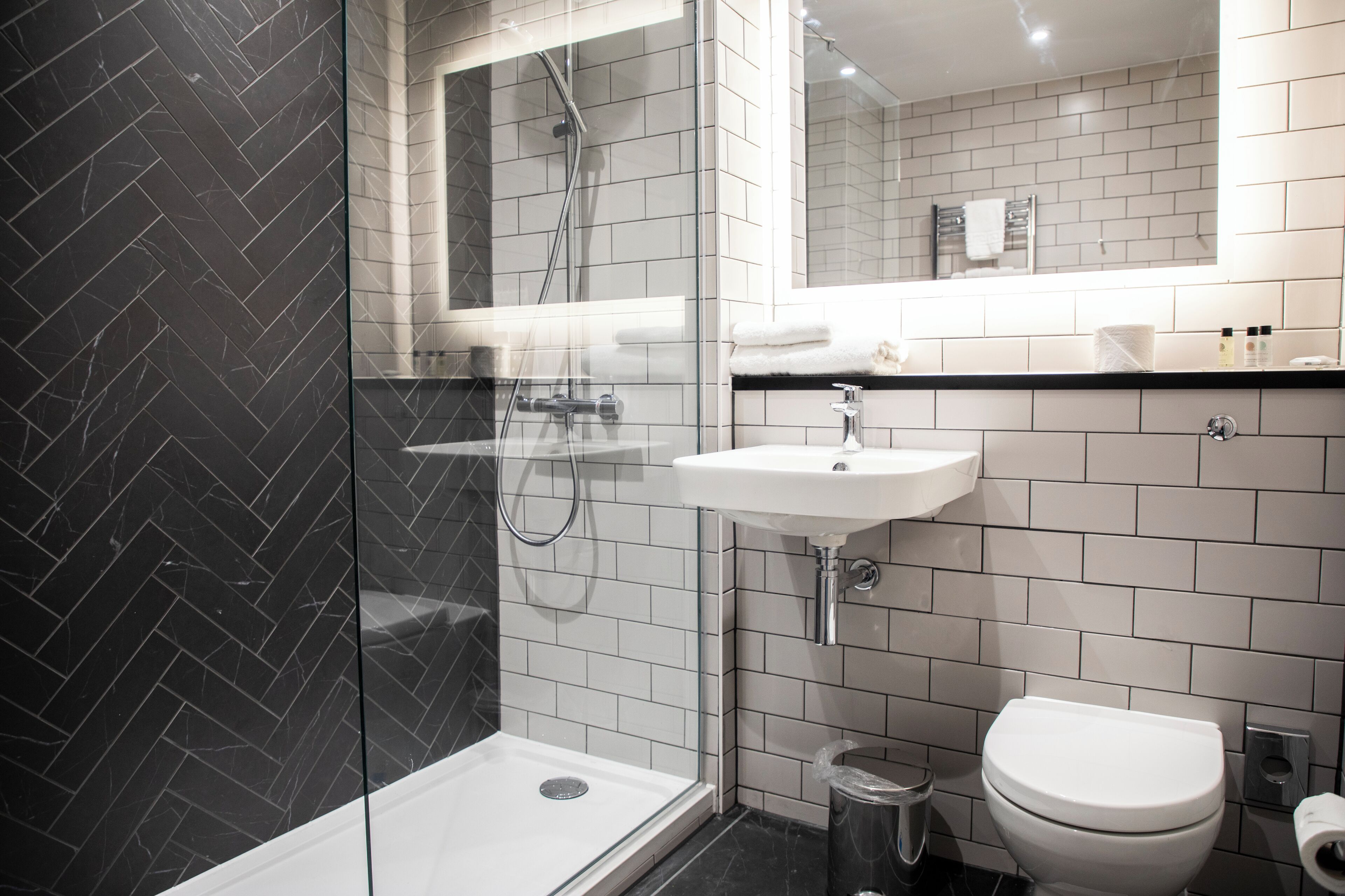 A modern bathroom with a glass shower enclosure, a white sink, and a toilet.