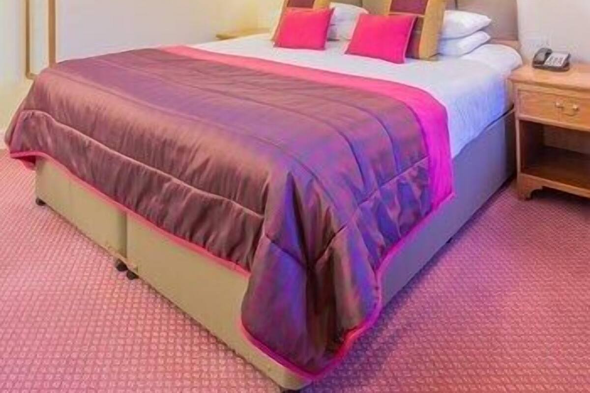 A hotel room with a bed, bedside tables, and a framed picture on the wall.