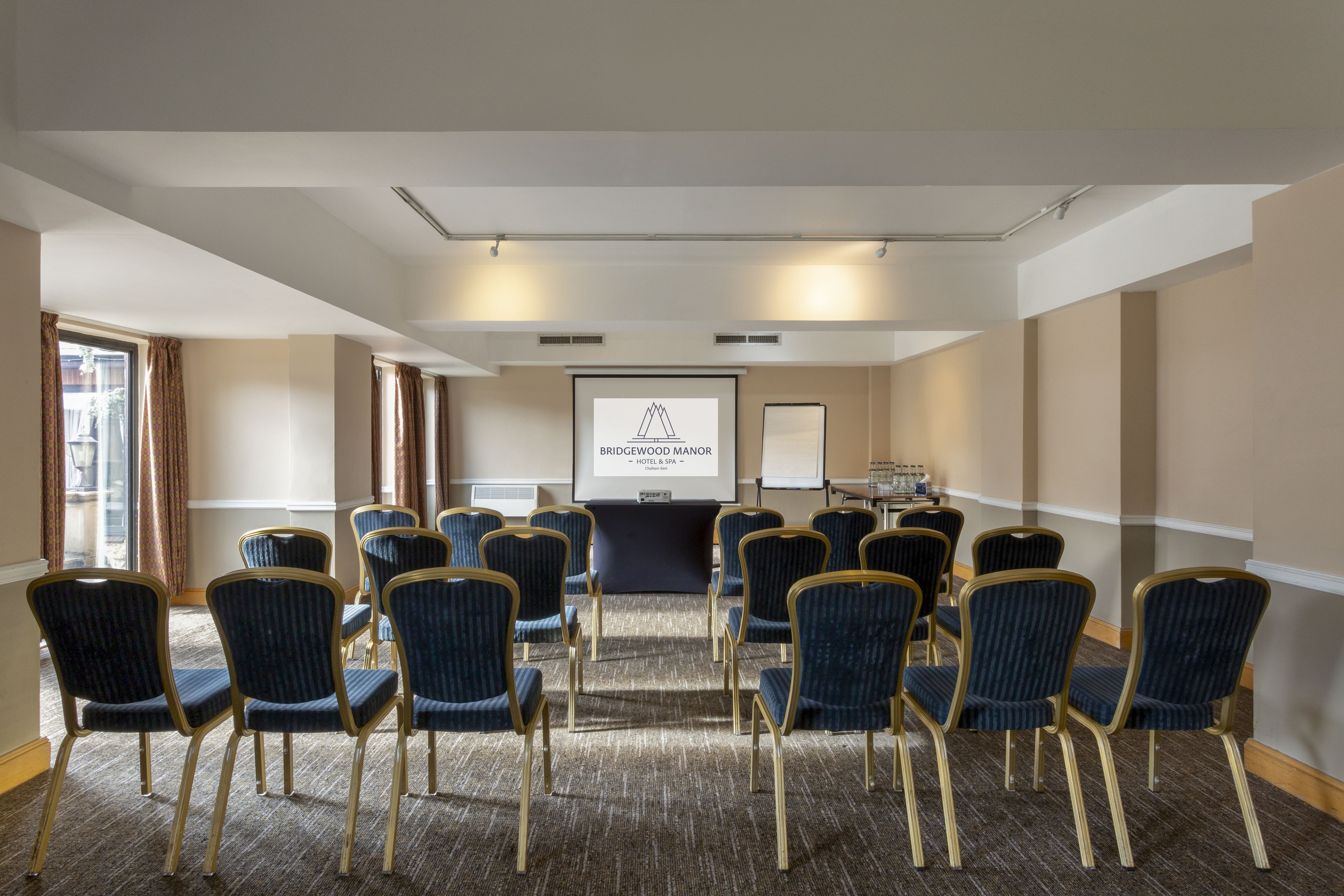 A conference room with rows of chairs, a projector screen, and a whiteboard.