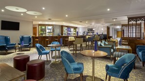 Un hall de hotel con zonas de estar, un bar y una pantalla de televisión.