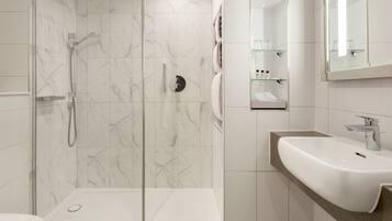 Une salle de bain moderne avec une douche à parois de verre, un lavabo blanc et un miroir au-dessus du lavabo.