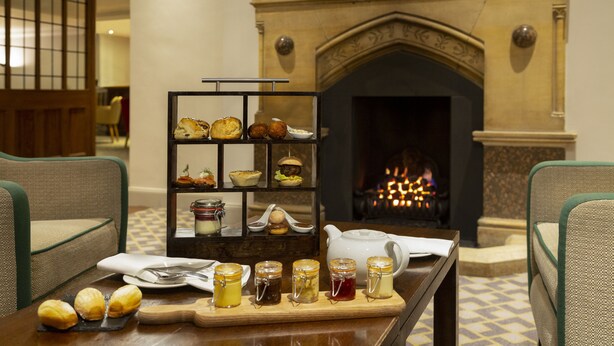 Una mesa de comedor con diversos pasteles y condimentos, una chimenea y una decoración de estilo tradicional.