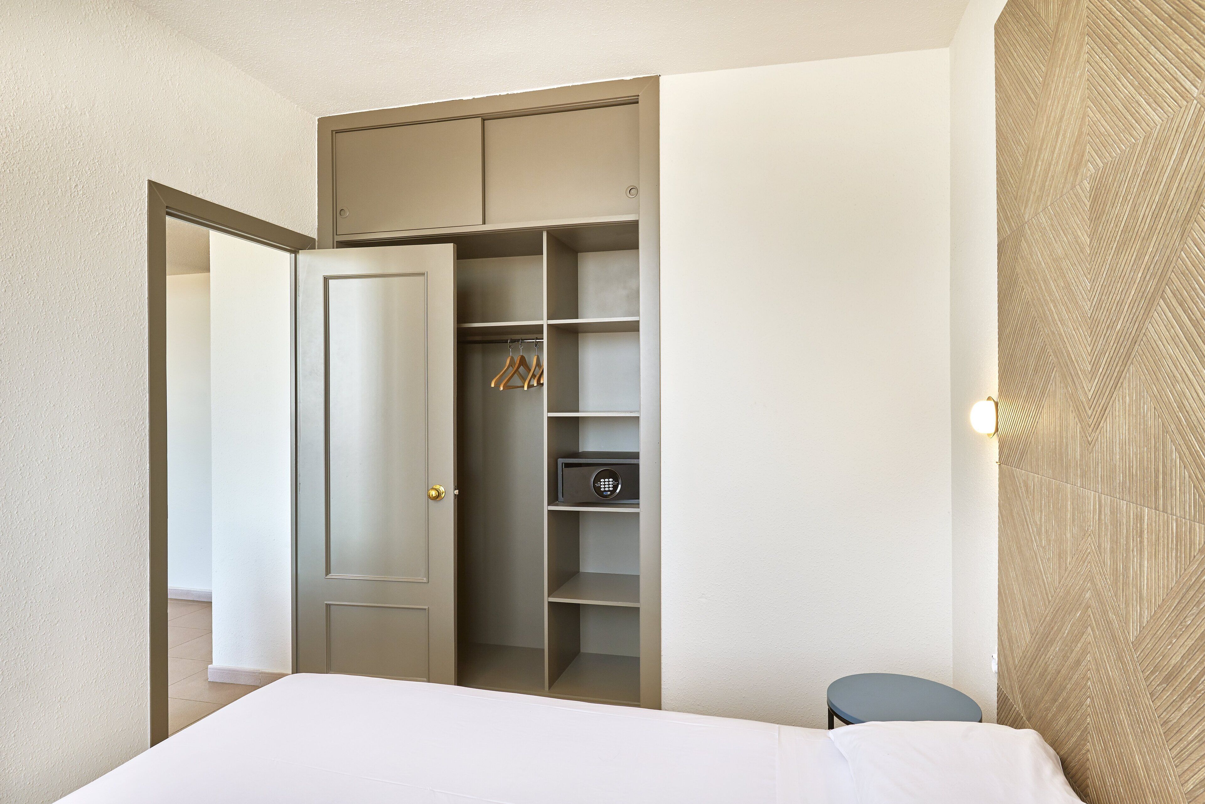 Une chambre à coucher comprenant un lit, une armoire avec espace pour suspendre les vêtements et une table de chevet.