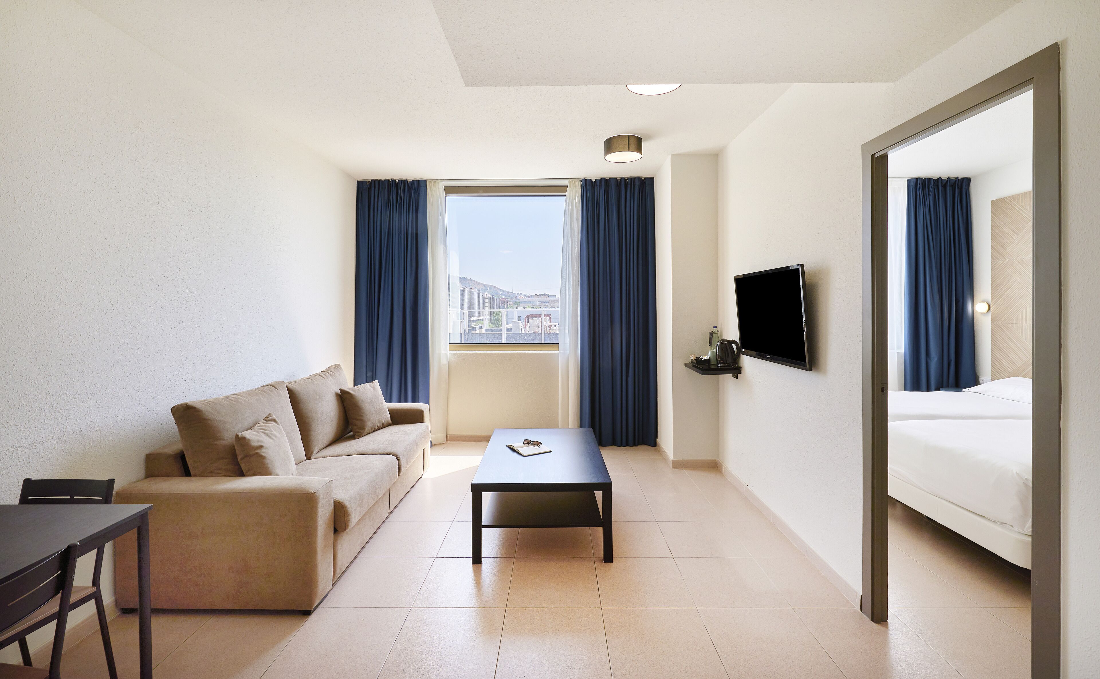 Een hotelkamer met een bank, een tafeltje, een televisie en een bed.