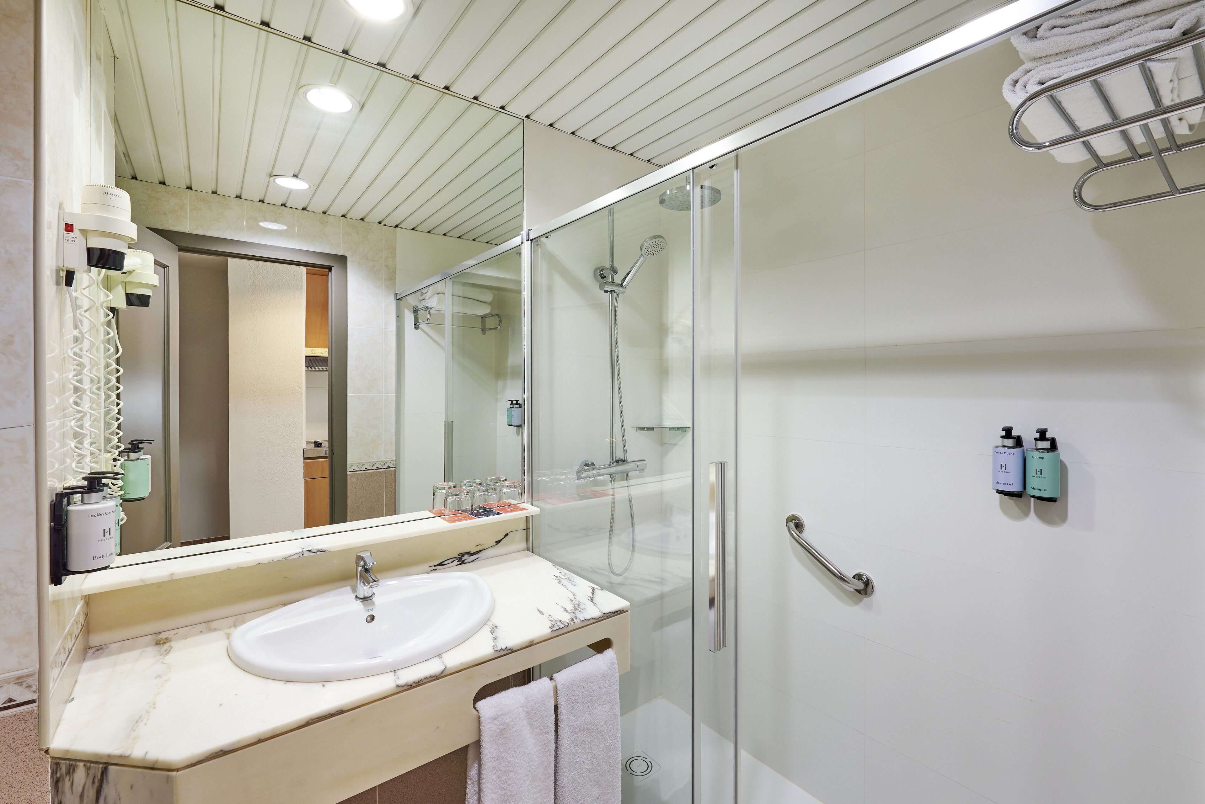 Un baño moderno con ducha de vidrio, lavamanos de mármol y un espejo grande.