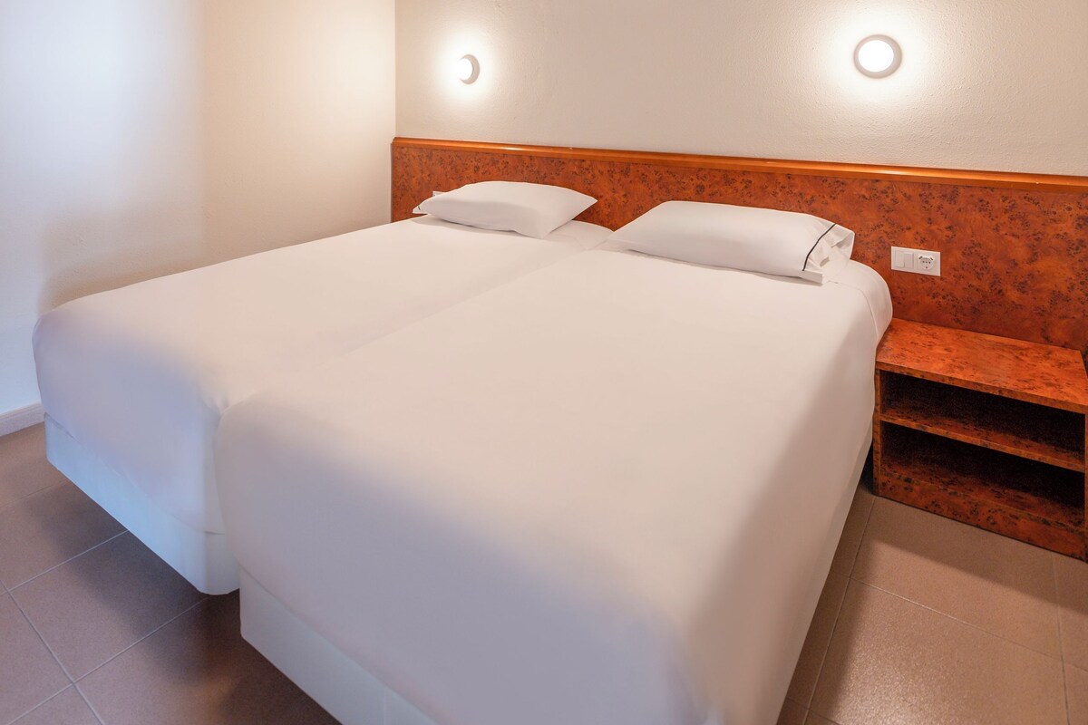 A hotel room with a large bed, two bedside tables, and a wooden headboard.