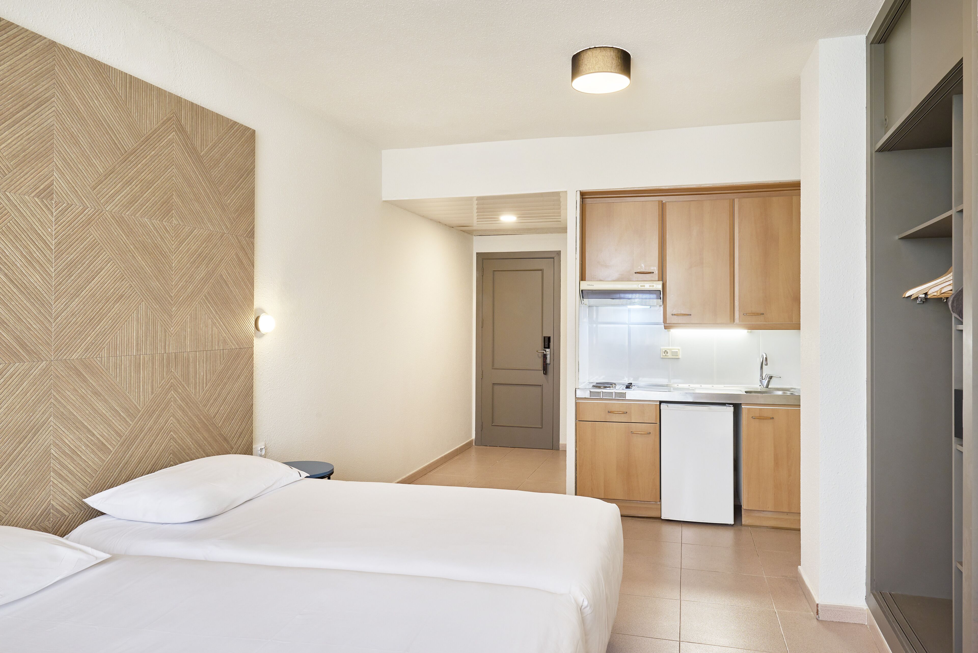 Una camera d'albergo con due letti, angolo cottura e bagno.