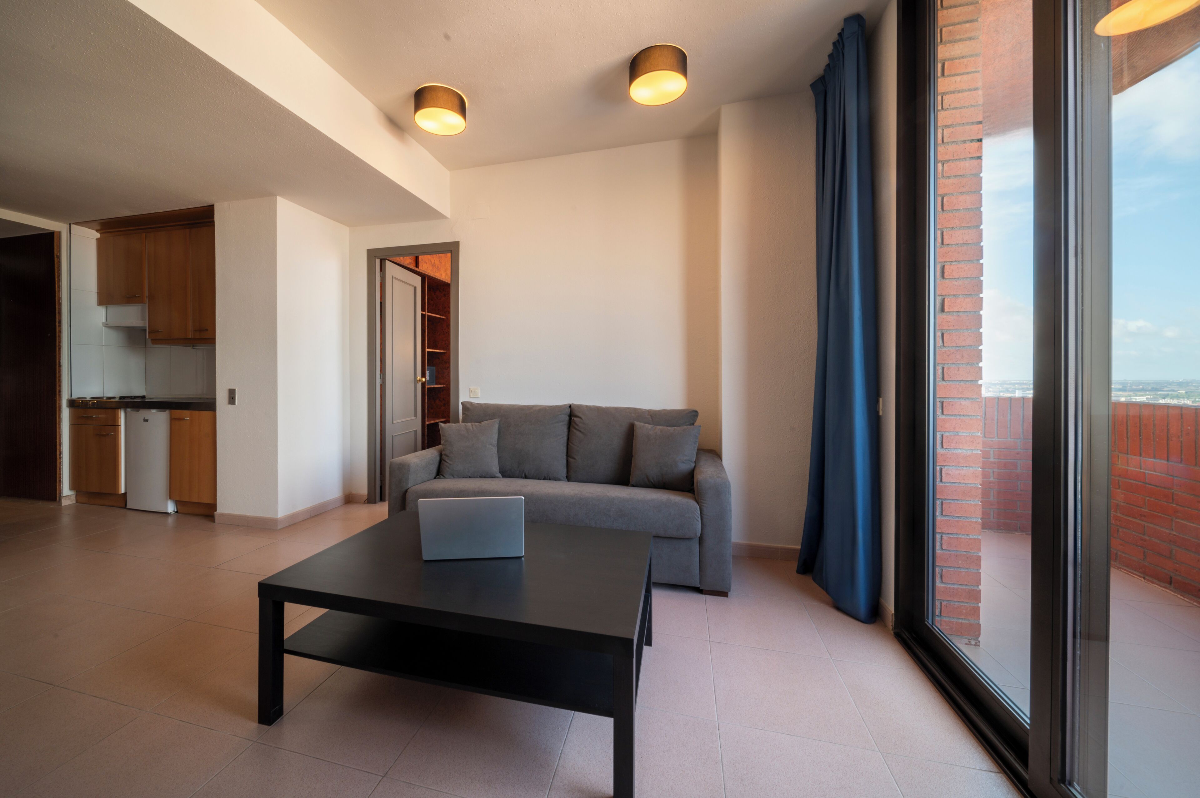 Een moderne woonkamer met een bank, een salontafel en een uitzicht op een stadslandschap door grote ramen.