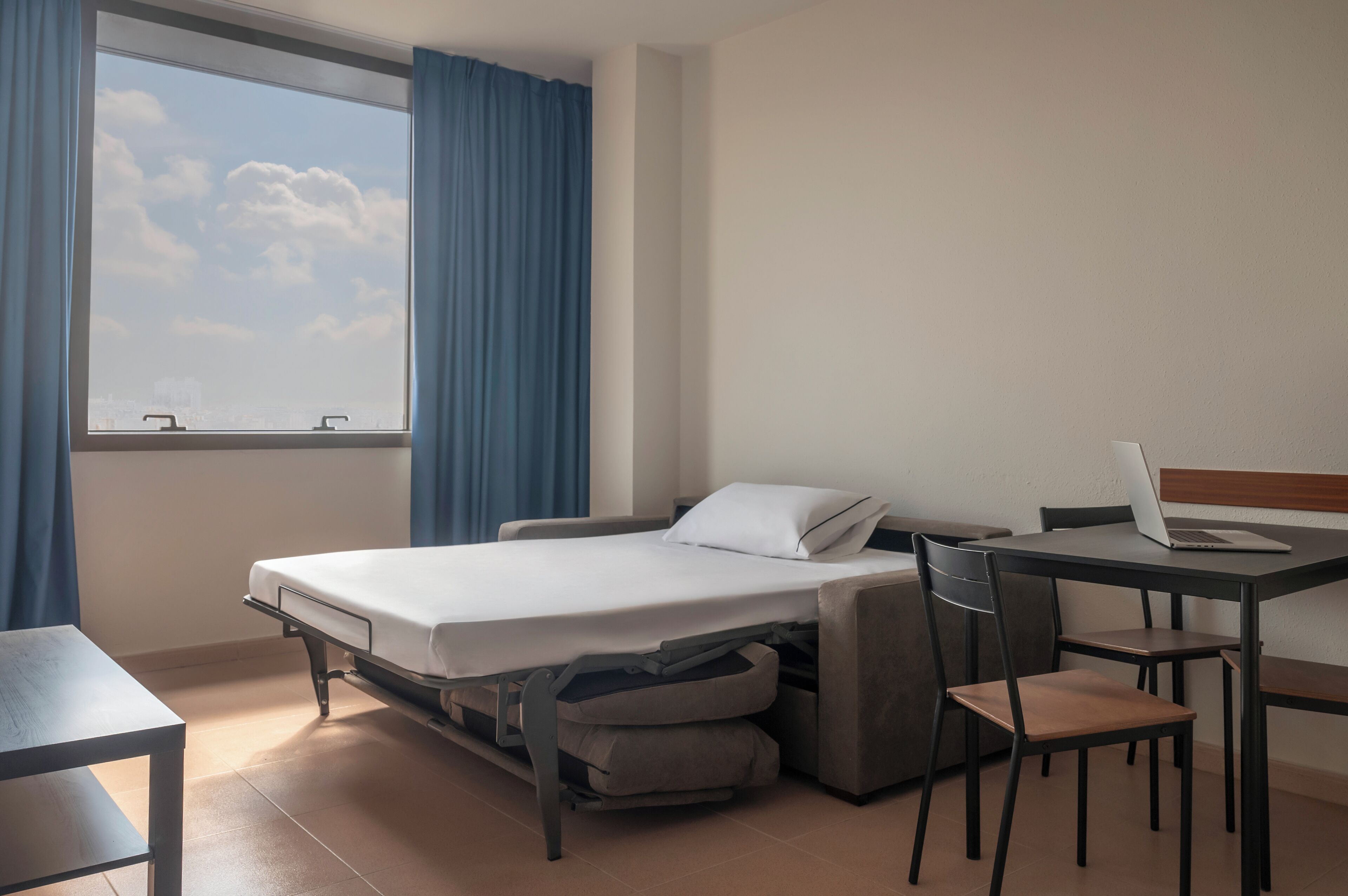 Habitación de hotel pequeña con una cama, un escritorio y una silla.