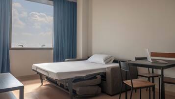 Habitación de hotel pequeña con una cama, un escritorio y una silla.