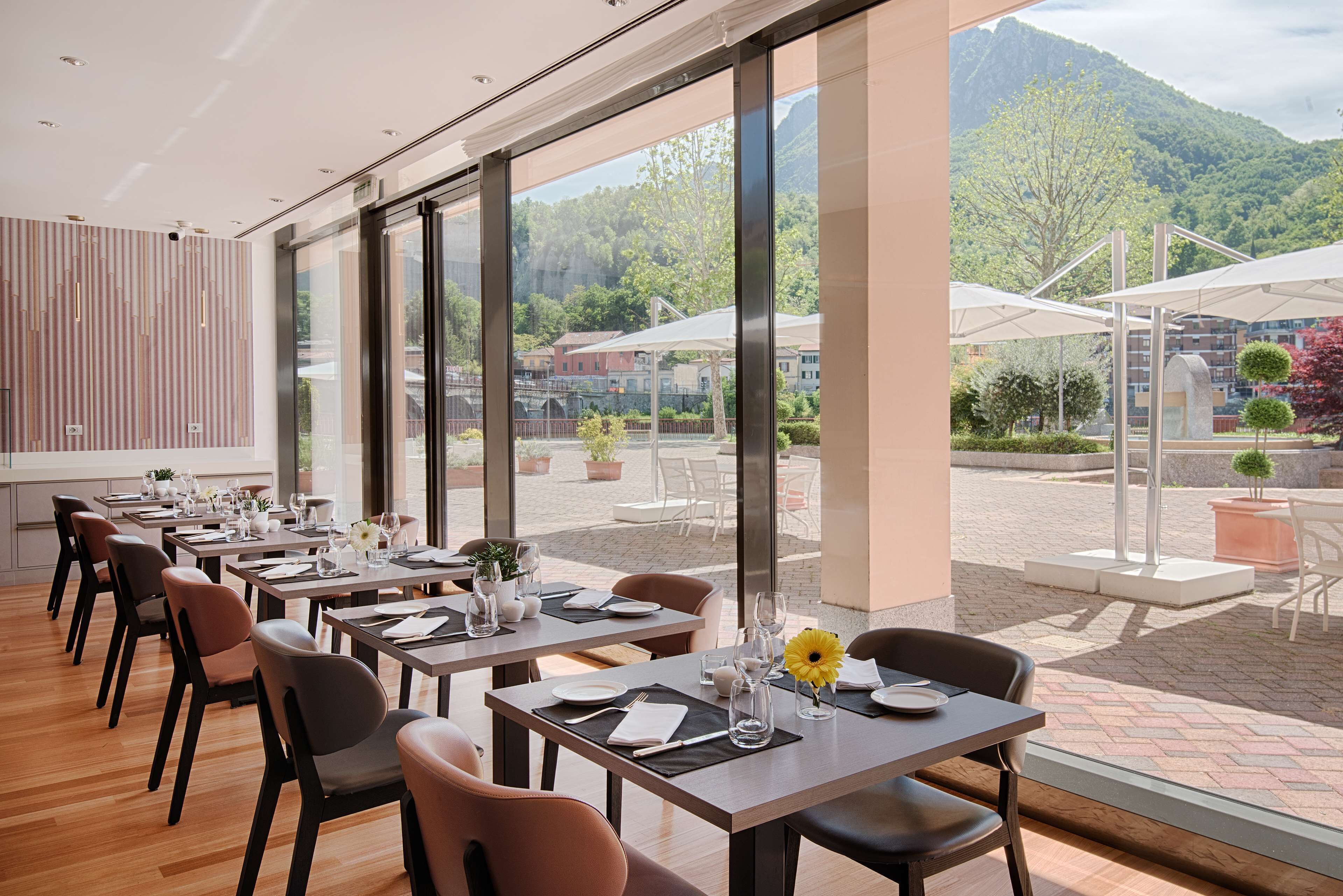 Un restaurante con mesas preparadas para comer, amplias ventanas que ofrecen vistas a un paisaje montañoso.