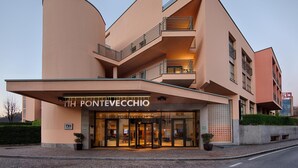 Un hôtel moderne à la façade incurvée, doté de nombreux balcons et d’une entrée imposante avec des portes en verre.